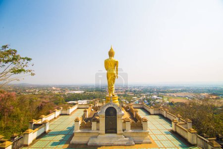 Foto de Estatua de buda dorada de pie en el templo de montaña mirada a la ciudad Nan Tailandia - Imagen libre de derechos
