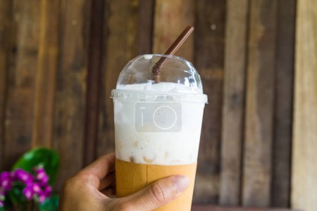 Foto de Mantenga la mano café con leche helada en fondo de cafetería vintage, bebida de verano - Imagen libre de derechos
