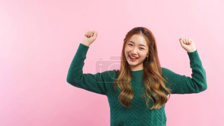 Téléchargez les photos : Jeunes femmes levant les bras avec un geste gagnant et souriant de bonheur isolé sur fond rose. - en image libre de droit