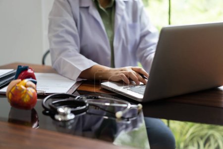 Female cardiologist doctor researching medical data on laptop to analysis cardiology treatment.