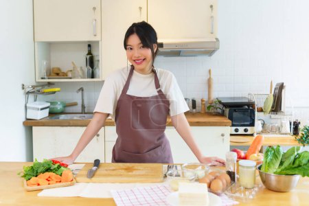 Téléchargez les photos : Femmes asiatiques couper des tranches de légumes frais sur planche à découper avec couteau pour préparer les ingrédients pour le petit déjeuner tout en appréciant de faire un mode de vie alimentaire sain dans la cuisine à la maison. - en image libre de droit