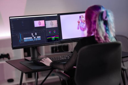 Professional creative digital artist immersed in editing video, surrounded by vibrant neon lights in modern video studio