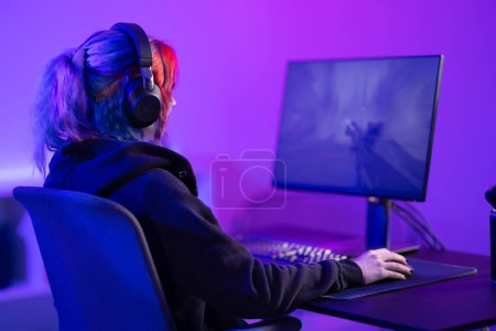 Professional gamer intensely playing a first-person shooter FPS video game, surrounded by vivid purple lighting in a modern gaming room setup.