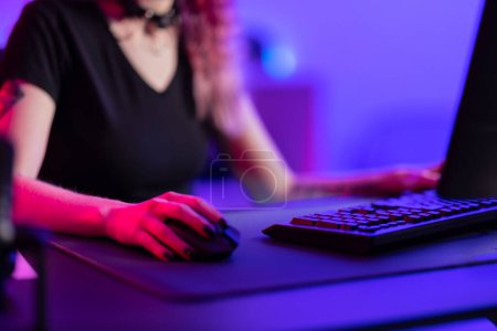 Ein professioneller Spieler beschäftigt sich intensiv mit einem Online-Spiel, das durch den lebhaften Schein eines farbenfrohen Spielraums mit modernem Spielgerät in Szene gesetzt wird..