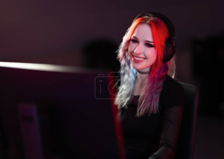A young professional gamer with a radiant smile plays a video game in a colorful, illuminated gaming room, showcasing modern gaming technology and lifestyle.