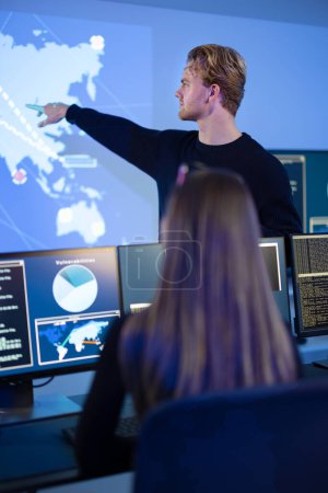 Close-up of a cyber security team protecting systems from security breach in a Cyber Security Operations Center SOC. One Chief Information Security Officer CISO and manager pointing on a map.