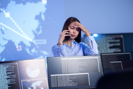 Focused and concerned confident female Cyber Security Analyst or Manager in enterprise Security Operations Center SOC. A team of security operators resolving a critical cybersecurity breach.