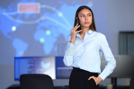 Focused confident female Cyber Security Analyst or Manager in enterprise Security Operations Center SOC. A team of security operators working with cybersecurity incidents and alerts.