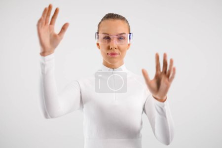 Une jeune femme vêtue d'un col roulé blanc interagissant avec une interface virtuelle futuriste, représentée par ses gestes de main. Mettre l'accent sur les concepts de technologie, d'innovation et d'interaction numérique.