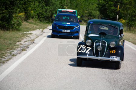Foto de URBINO, ITALIA - 16 JUN - 2022: FIAT 508 C BALILLA 1100 BERLINA 1939 en un viejo coche de carreras en el rally Mille Miglia 2022 la famosa carrera histórica italiana - Imagen libre de derechos