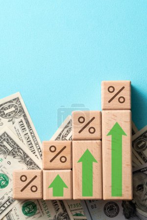 Foto de Bloques de madera con tasa de interés por ciento del banco con dólares estadounidenses, concepto de diseño de crisis de la economía mundial financiera sobre fondo de tabla azul. - Imagen libre de derechos
