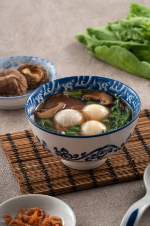 Foto de Comer yuanxiao tangyuan grande (tang yuan, bolas de masa de arroz glutinoso) con sopa salada en un tazón para el festival del solsticio de invierno. - Imagen libre de derechos