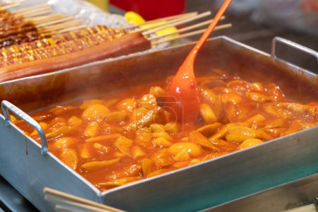Photo for Delicious Korean cuisine Tteokbokki, tasty spicy rice cake with sausages, eggs in market for street food snacks. - Royalty Free Image