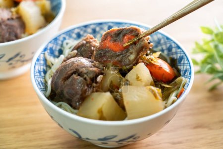 Beef noodle soup. Taiwanese famous food with sliced red braised beef and vegetables in a bowl on wooden table background.
