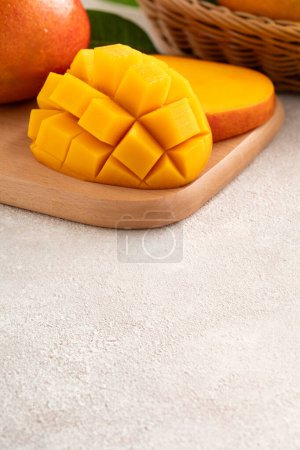 Frisch geschnittene, geschnittene, gewürfelte reife Mango auf grauem Tischhintergrund mit Blatt zum Essen.