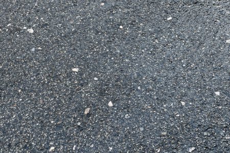 Details of the textured asphalt road background which is made of asphalt and small stones.