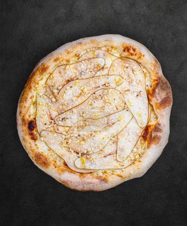 Photo for Pizza Gorgonzola with pear, walnuts, syringa sauce, truffle oil. Neapolitan round pizza on dark background - Royalty Free Image