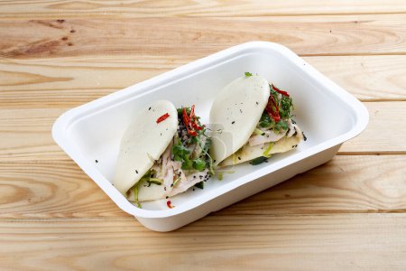 Foto de Bollos de arroz al vapor "Bao" con pollo. Comida saludable. Comida para llevar. Sobre un fondo de madera. - Imagen libre de derechos