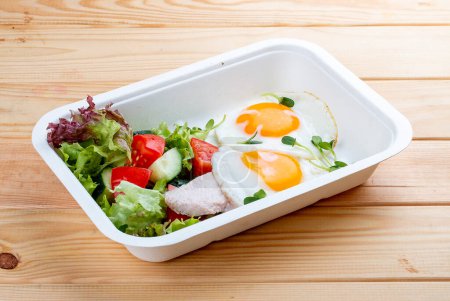 Fried eggs and turkey. Healthy diet. Takeaway food.  On a wooden background.