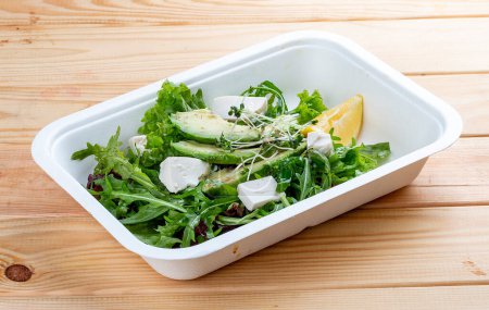Mezcla de ensaladas (verduras, aguacate y tofu). Comida saludable. Comida para llevar. Sobre un fondo de madera.