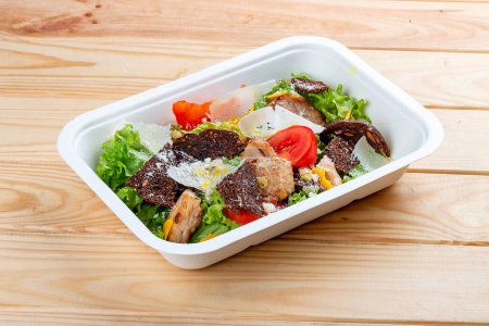 Fitness Caesar Salat mit Huhn. Gesunde Ernährung. Essen zum Mitnehmen. Auf einem hölzernen Hintergrund.