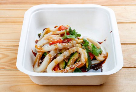 Squid with vegetables in "Teriyaki" sauce. Healthy diet. Takeaway food.  On a wooden background.