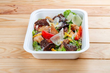 Téléchargez les photos : Fitness Salade César au poulet. Une nourriture saine. De la nourriture à emporter. Sur un fond en bois. - en image libre de droit