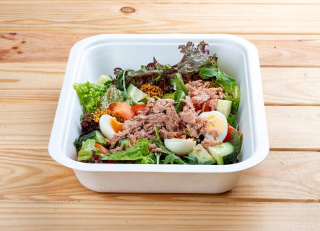 Tuna salad with tuna and quail eggs. Healthy food. Takeaway food.  On a wooden background.