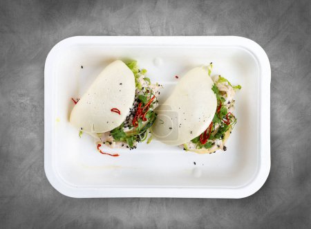 Gedämpfte Reisbrötchen "Bao" mit Hühnchen. Gesunde Ernährung. Essen zum Mitnehmen. Draufsicht, auf grauem Hintergrund.