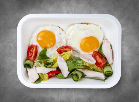 Photo for Fried eggs and turkey. Healthy diet. Takeaway food.  Top view, on a gray background. - Royalty Free Image