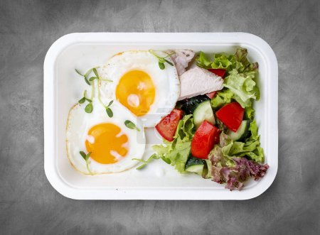 Fried eggs and turkey. Healthy diet. Takeaway food.  Top view, on a gray background.