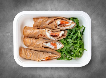 Buckwheat pancakes with salmon. Healthy food. Takeaway food. Top view, on a gray background.