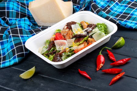 Fitness Caesar salad with chicken. Healthy food. Takeaway food. On a wooden background.
