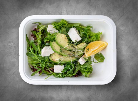 Mezcla de ensaladas (verduras, aguacate y tofu). Comida saludable. Comida para llevar. Vista superior, sobre un fondo gris.