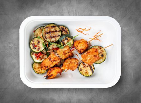 Grilled chicken kebab with zucchini. Healthy diet. Takeaway food.  Top view, on a gray background.