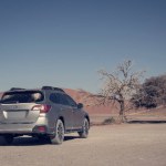Grey Subaru Outback in the middle of a desert in Namibia on a hot sunny day