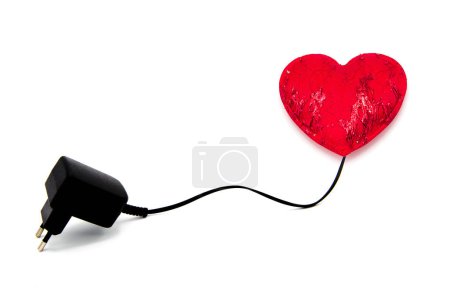 Foto de Red heart connected to cable with socket for charging isolated on white background. - Imagen libre de derechos