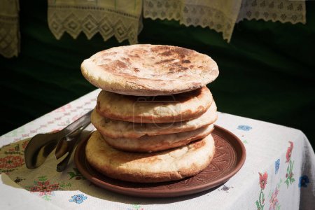 Photo for Palyanytsya fragrant Ukrainian bread. Traditional Ukrainian flatbreads in a clay plate on the table. - Royalty Free Image