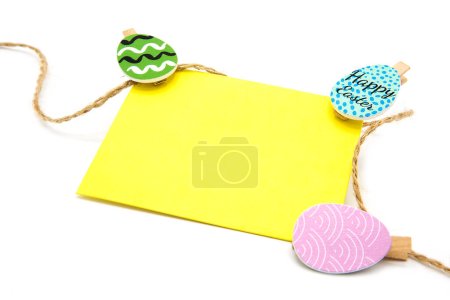Greeting blank card hanging on a rope on clothespins with colored eggs. Copy space. Free space for text. Happy easter!