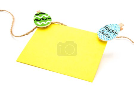 Greeting blank card hanging on a rope on clothespins with colored eggs. Copy space. Free space for text. Happy easter!