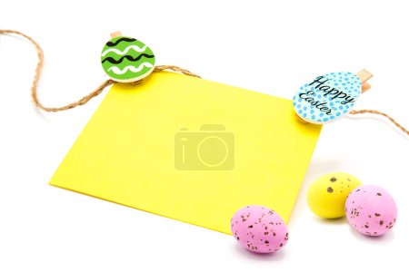 Grußkarte mit Strick auf Wäscheklammern mit bunten Eiern auf weißem Hintergrund. Kopierraum. Freiraum für Text. Frohe Ostern!