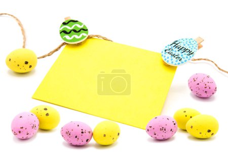 Greeting blank card with rope on clothespins with scattered colored eggs isolated on a white background. Copy space. Free space for text. Happy easter!