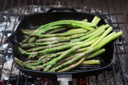 Photo for Grilled asparagus. Pile of buttered asparagus spears roasting on an outdoor grill. - Royalty Free Image