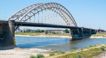 Foto de Nijmegen, Países Bajos, 11 de agosto de 2022: El río Waal bajo el puente Waal en Nijmegen está por debajo del nivel del indicador de agua debido al verano seco y al calentamiento global - Imagen libre de derechos