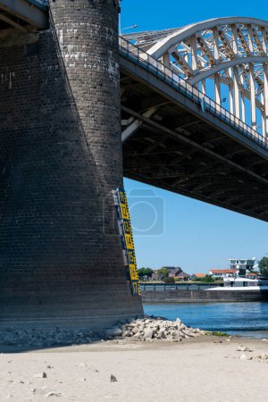 Photo for Nijmegen, The Netherlands, August 11, 2022:  Water level is below the level of the water indicator because of global warming, at the a bridge over the river - Royalty Free Image