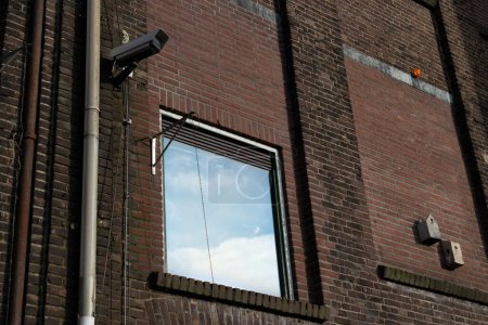 Téléchargez les photos : Ancien bâtiment rénové avec une caméra de sécurité et une fenêtre - en image libre de droit