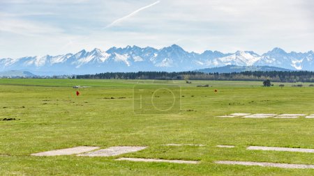 View of snow capped Tatra mountains from sport grass airfield in Nowy Targ