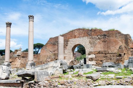The remnants of the Roman Forum stand under a clear blue sky, featuring columns and arches that echo the grandeur of ancient Rome.