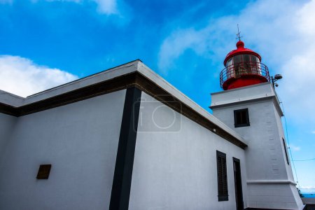 Téléchargez les photos : Vieux phare rouge et blanc avec maison silhouette contre ciel bleu a Ponta do Pargo au nord madère portugal - en image libre de droit