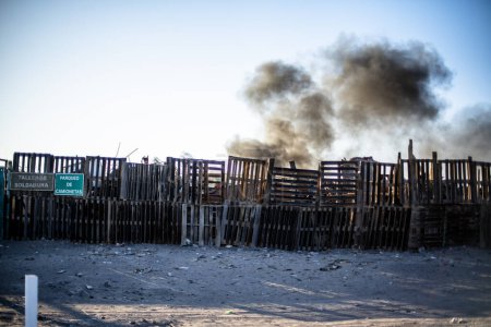 Photo for Barricade made of old wooden pallets separate the road from accidental fires with black smoke as if they were war zones separating disasters in Peru - Royalty Free Image